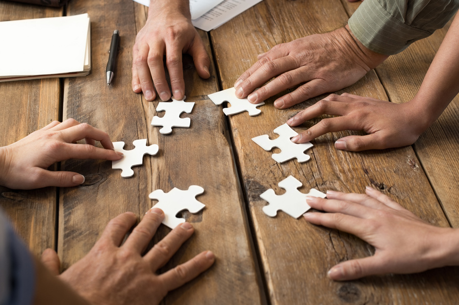 Puzzleteile auf einem Tisch und Hände